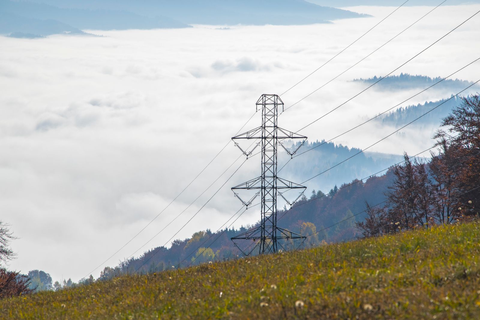 Transmission tower in fog in front of mountains